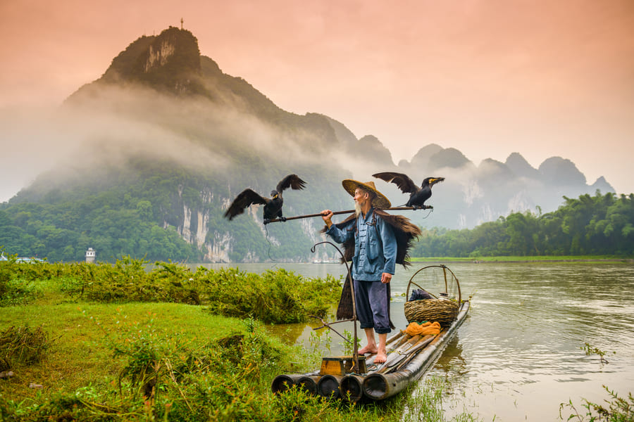 Pescador con aves volando a su alrededor